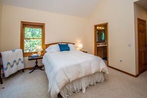 Een slaapkamer met een bed, nachtkastje, lamp, stoel, raam en deur.