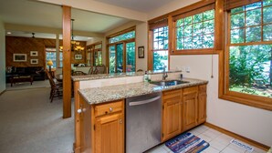 A kitchen with wooden cabinets, granite countertops, and large windows.