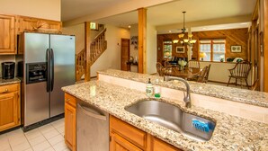 A kitchen with granite countertops, stainless steel appliances, wooden cabinets, and a large sink.