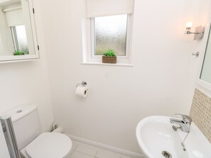 Ein Badezimmer mit Toilette, Bidet, Waschbecken und einem kleinen Fenster mit Pflanze.