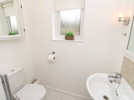Un baño con inodoro, bidé, lavabo y una pequeña ventana con una planta.