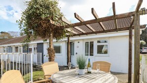 A patio with wicker furniture, a round table, and a pergola. - 8 Munday Cottages (Yarmouth)