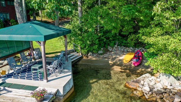 A wooden dock with chairs and a covered seating area, a clear water feature, and a kayak. - Lake Winnipesaukee Waterfront Rental Wolfeboro NH Dock Sleeps 13 (Wolfeboro)