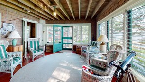 A cozy room with wicker furniture, a wooden ceiling, and large windows. - Lake Winnipesaukee Waterfront Rental Wolfeboro NH Dock Sleeps 13 (Wolfeboro)