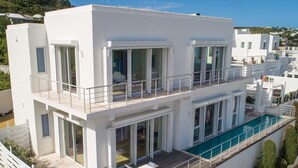 A modern two-story building with a rooftop pool, large windows, and a balcony. - ☀️👙Sea Fan by IRE Vacations - Exquisite Villa With Views from Each Bedroom (Oyster Pond)