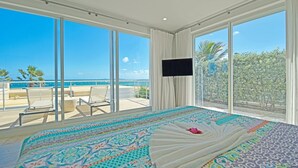 A hotel room with a large bed, a TV, and a balcony with a view of the ocean. - ☀️👙Sea Fan by IRE Vacations - Exquisite Villa With Views from Each Bedroom (Oyster Pond)