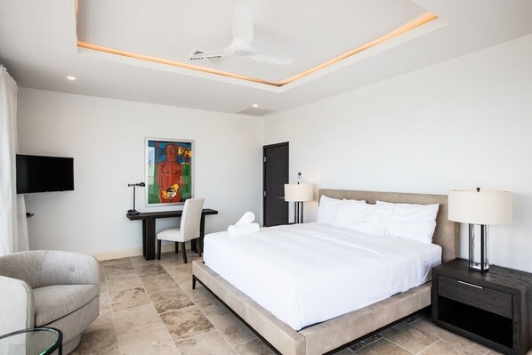 Une chambre d’hôtel moderne équipée d’un grand lit, d’un bureau, d’une chaise, d’une télévision et d’un ventilateur de plafond.