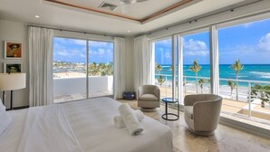 A hotel room with a large bed, a ceiling fan, and a view of the beach. - ☀️👙Sea Fan by IRE Vacations - Exquisite Villa With Views from Each Bedroom (Oyster Pond)