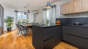 Una cocina moderna con una isla central, armarios negros y un comedor con vistas.