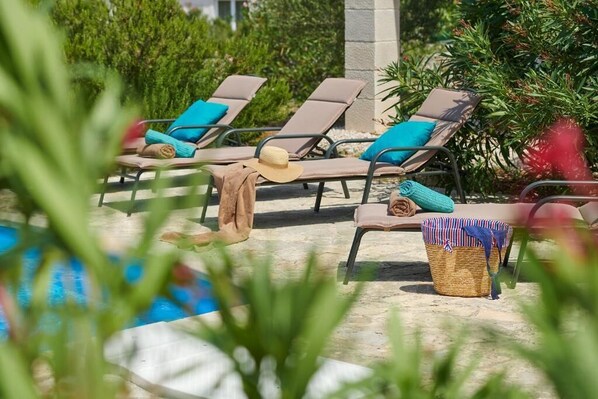 A poolside area with lounge chairs and a wicker basket.