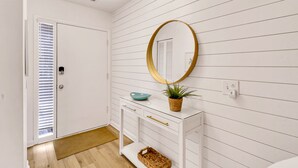 A hallway with white walls, a white door, a white console table with a mirror, a bowl, and a plant. - Pet Friendly Beachside Villa - Across the Street from the Beach! (Hilton Head Island)