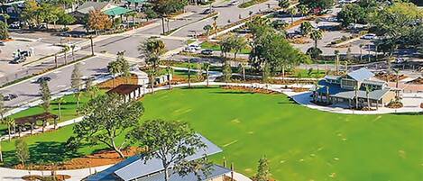 A resort with a large green lawn, a parking area, and a view of the ocean.