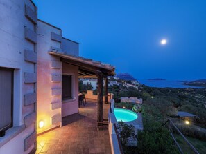Eine Villa mit Pool, Sitzgelegenheiten im Freien und Meerblick.