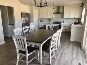 Une cuisine moderne avec des meubles blancs, un îlot central et une table à manger avec des chaises.