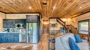 A spacious kitchen with modern appliances, a bar area, and a cozy seating space with a leather couch. - Luxury Mountain Cabin for Families & Groups | 4 King Bedrooms + Hot Tub (Epworth)