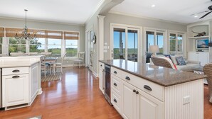 Una cocina amplia con una isla grande, piso de madera y vistas al exterior a través de amplios ventanales.