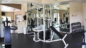 A gym with various exercise equipment, including a squat rack, benches, and dumbbells.