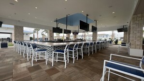 Un vaste espace bar extérieur doté de plusieurs coins salons et d’un comptoir central.
