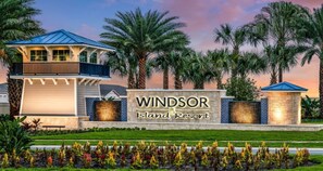 A sign for Windsor Island Resort with a modern building and palm trees. - Last Minute Disney! Private Pool, Hot Tub, Game Room & Themed Bedrooms. Book Now! #56665 (Orlando)