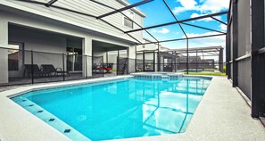 Una piscina interna rettangolare con acqua cristallina, circondata da un portico coperto con posti a sedere e vista su un edificio sullo sfondo.