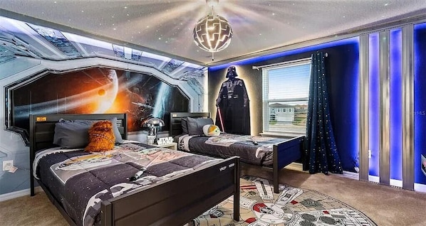 A bedroom with a Star Wars theme, including a mural, Darth Vader figure, and themed bedding.