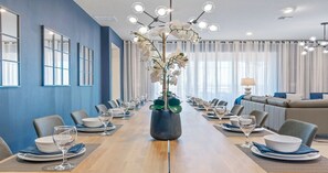 Une salle de conférence avec une longue table préparée pour une réunion, entourée de chaises, et un canapé à l’arrière-plan.