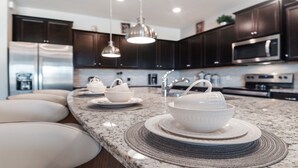 A modern kitchen with dark wood cabinets, stainless steel appliances, and a granite countertop. - Last Minute Disney! Private Pool, Hot Tub, Game Room & Themed Bedrooms. Book Now! #56653 (Orlando)