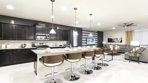 A modern kitchen with dark cabinets, stainless steel appliances, and a central island with bar stools. - Last Minute Disney! Private Pool, Hot Tub, Game Room & Themed Bedrooms. Book Now! #56609 (Orlando)