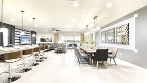 A modern kitchen with a dining area, featuring a large island, bar stools, and a ceiling fan. - Last Minute Disney! Private Pool, Hot Tub, Game Room & Themed Bedrooms. Book Now! #56609 (Orlando)