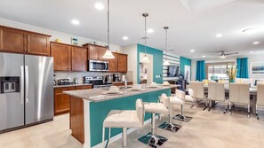 Enjoy cooking in this well-equipped kitchen with a central island and bar stools, offering a view of the adjacent dining area.