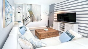 Relax in this stylish living room with a sofa, coffee table, flat-screen TV, and a beautiful abstract painting.