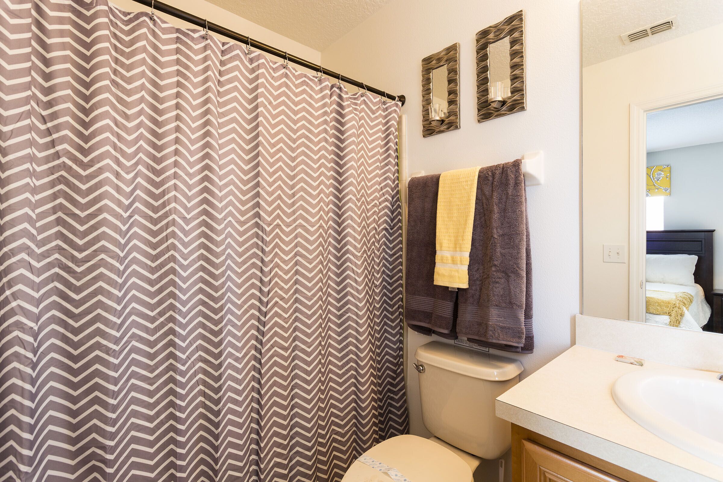 A bathroom with a shower curtain, a toilet, a sink, and towels.
