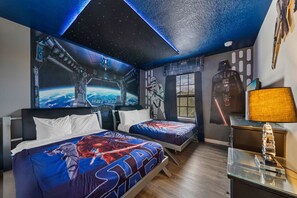 Ein Zimmer mit zwei Betten, einer Wandmalerei zum Thema Star Wars, einem Star Wars-Poster und einer Lampe auf einem Nachttisch.