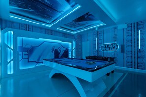 Ein futuristisches Zimmer mit Billardtisch, Star Wars-Dekoration und einem hochmodernen Deckenstil.
