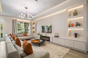 Ein modernes Wohnzimmer mit einer Eckcouch, einem Couchtisch, einem Flachbildfernseher und Einbauschränken mit Dekorationselementen.