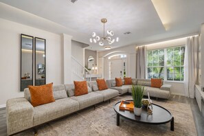 Ein modernes Wohnzimmer mit einem Ecksofa, einem runden Couchtisch und einem großen Fenster mit Vorhängen.