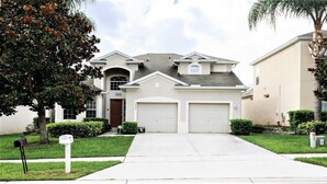 A two-story house with a garage, a front yard, and a mailbox. - Last Minute Disney! Private Pool, Hot Tub, Game Room & Themed Bedrooms. Book Now! #56545 (Orlando)