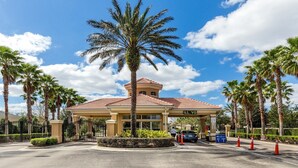 L'ingresso di un hotel con una palma, un vialetto recintato e un cielo azzurro.