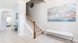 Staircase leads to an upper level, with a bench and abstract art above.