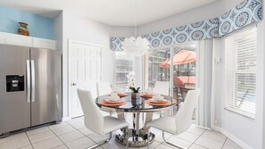 Enjoy meals in this kitchen and dining area with a round table for four, an oven, and a stainless steel refrigerator.