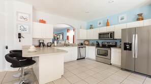 Enjoy cooking in this well-equipped kitchen with a refrigerator, microwave, and oven, plus a convenient bar area with seating.