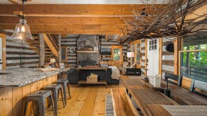 A rustic log cabin interior with a kitchen, dining area, and seating.