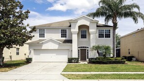 Traditional two-story home with a central entrance, garage, and beautifully manicured lawns.