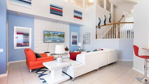 Un salón moderno con un sofá blanco, un sillón rojo y un televisor de pantalla plana.