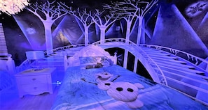 A themed bedroom with a bed, nightstands, and a wall mural.