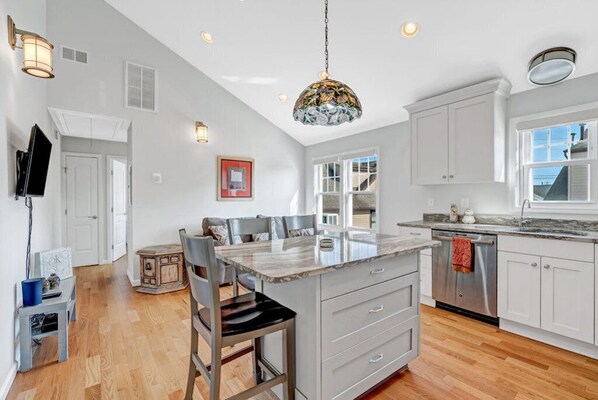A spacious kitchen with a large island, white cabinetry, and a modern pendant light.