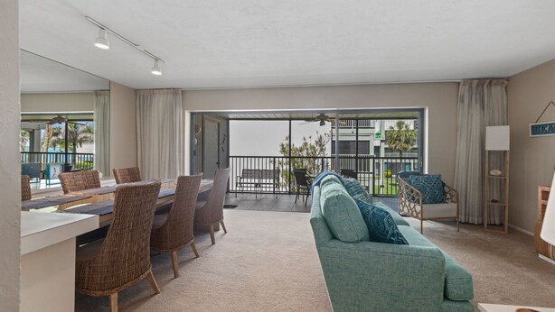 Un salon moderne comprenant un coin repas, un canapé et un balcon offrant une vue sur les palmiers.