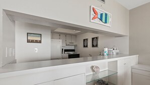 Une cuisine moderne avec des meubles blancs, une étagère en verre et un îlot central.