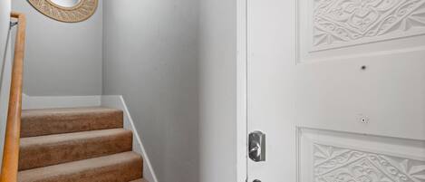 A staircase with carpeted steps leading to a white door with decorative paneling.