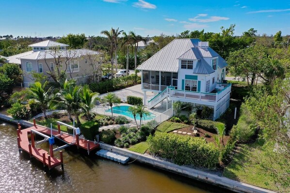 A large house with a pool, a dock, and a garden.